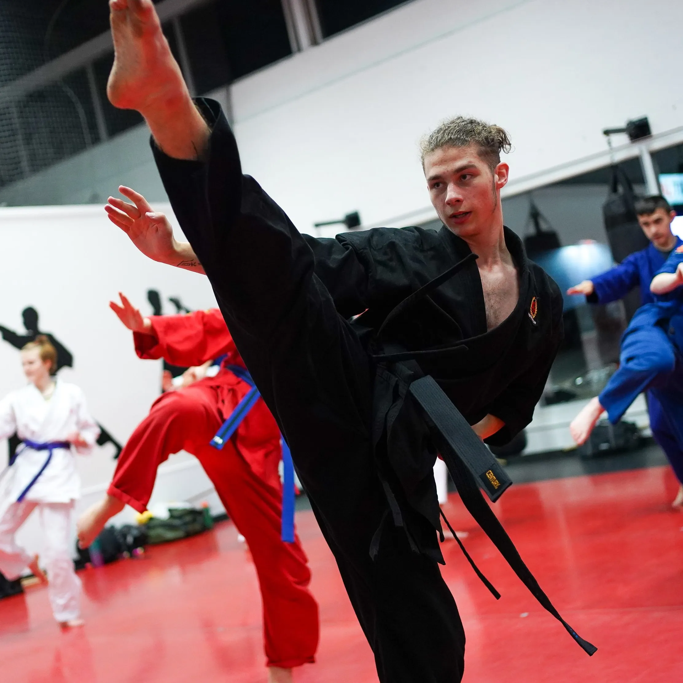 A black belt throwing a high kick in the teen and adult karate class