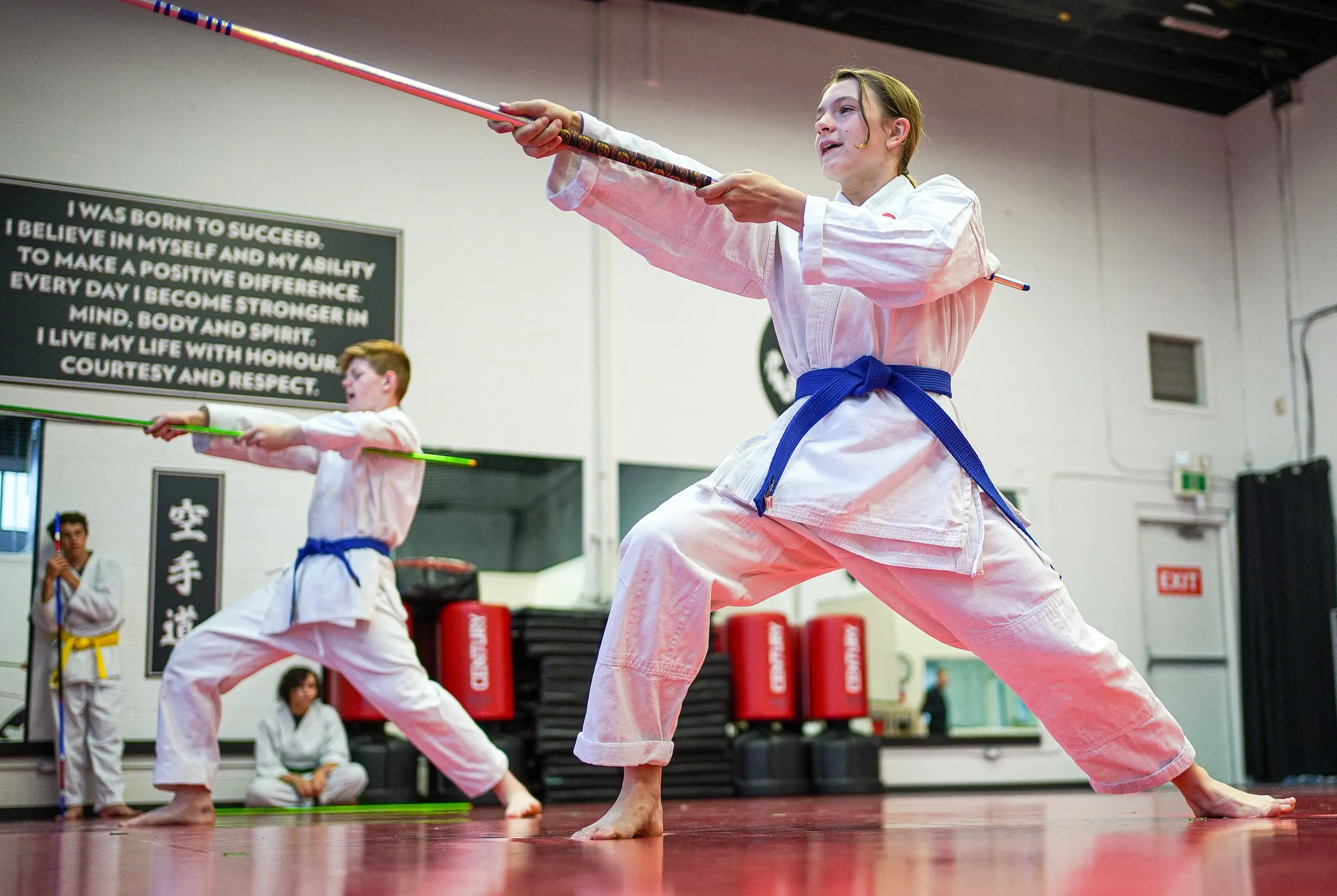 An adult student training with a bo staff