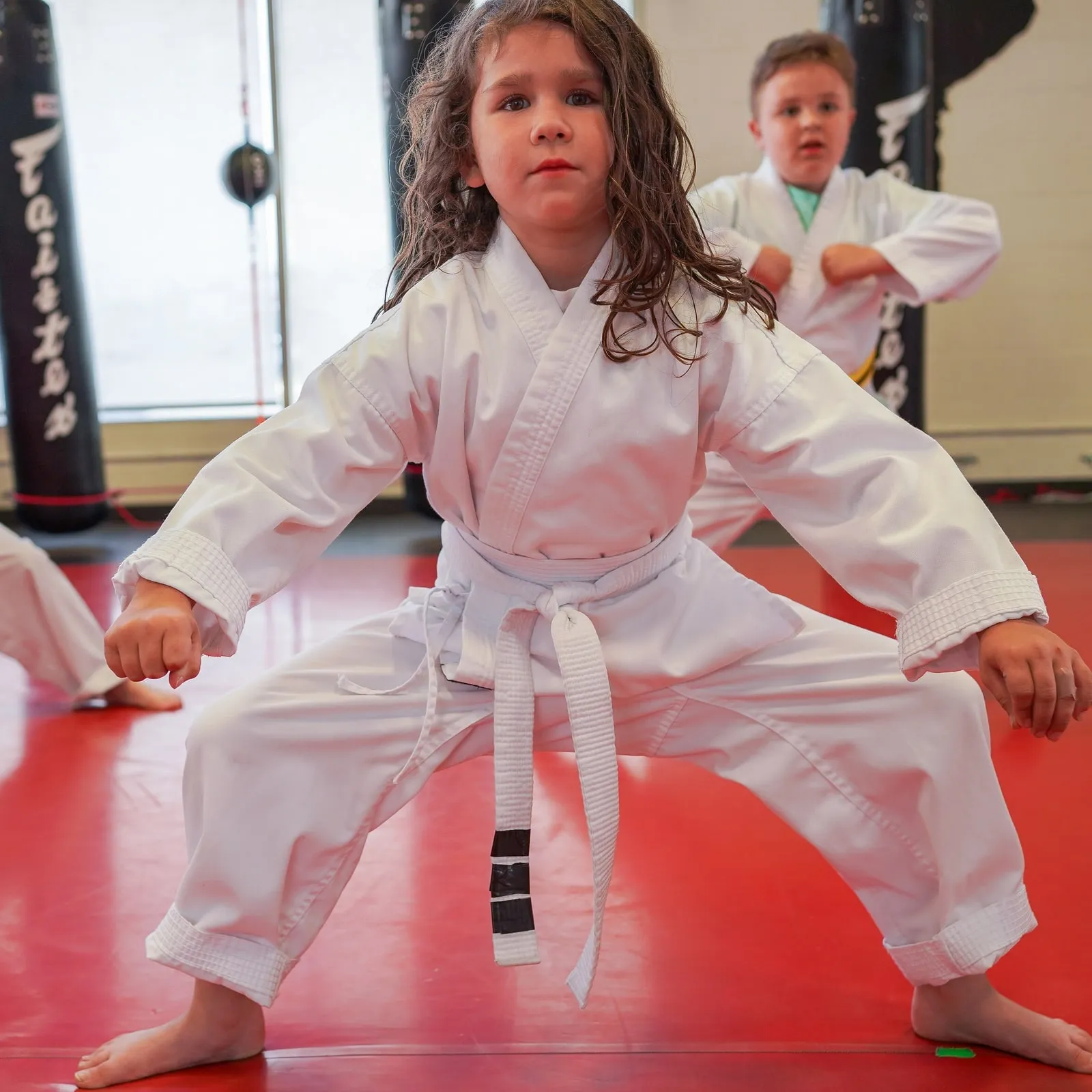 A young girl in a white uniform holding a strong karate stance
