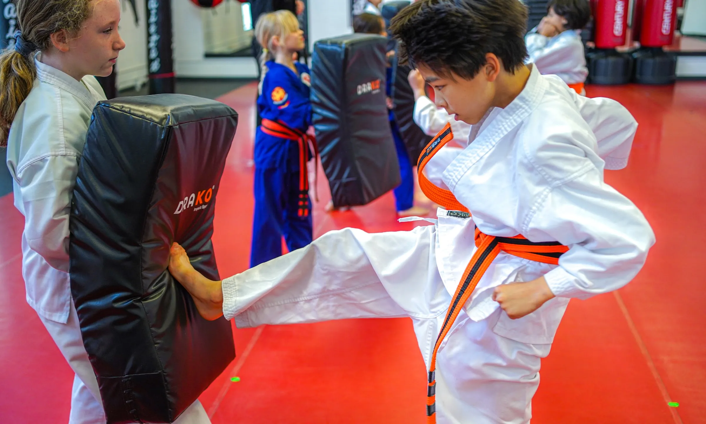 A student kicking a kick shield held by a classmate