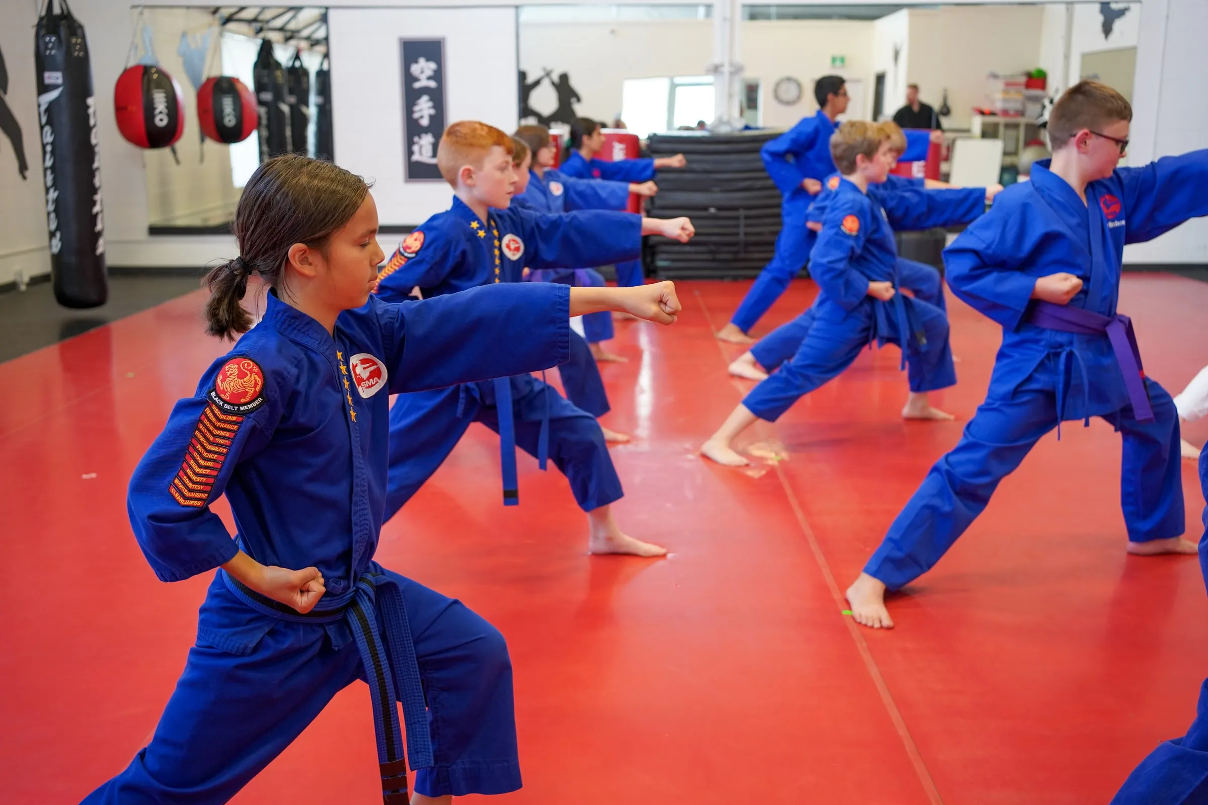 A line of junior students punching together in blue uniforms