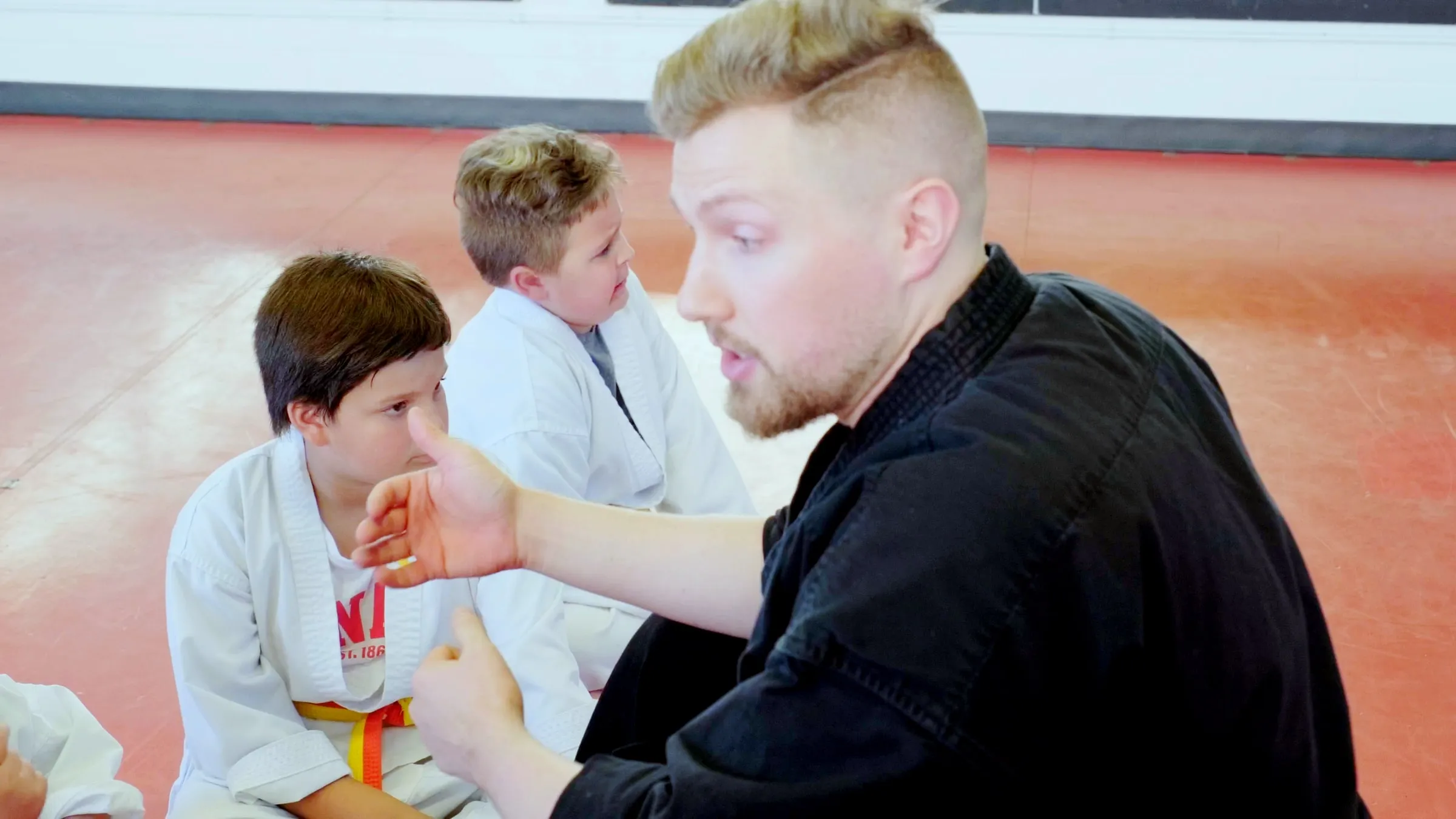 Sensei Troy kneeling to talk with young students